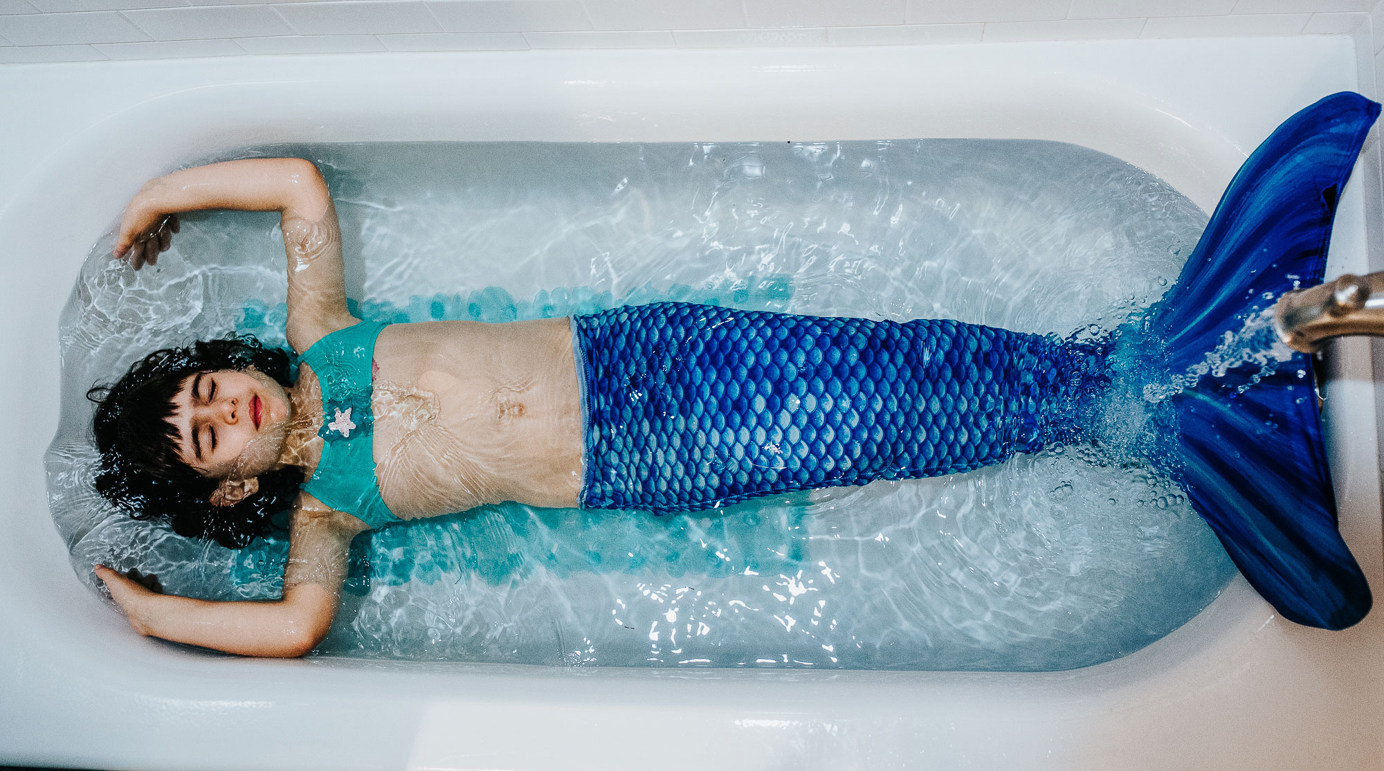 girl dressed up as a mermaid in the bath tub