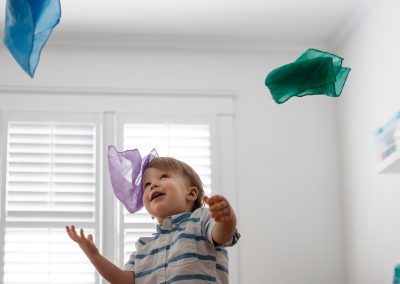little child playing with colorful tissue in the air