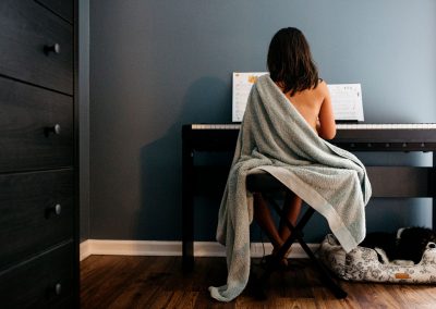 girl playing piano in a blu towel in the bedroom