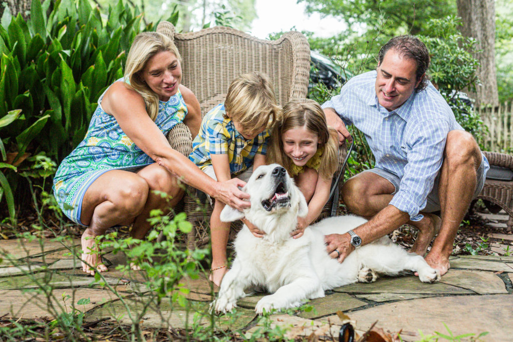family of four with a dog sitting in the grass
